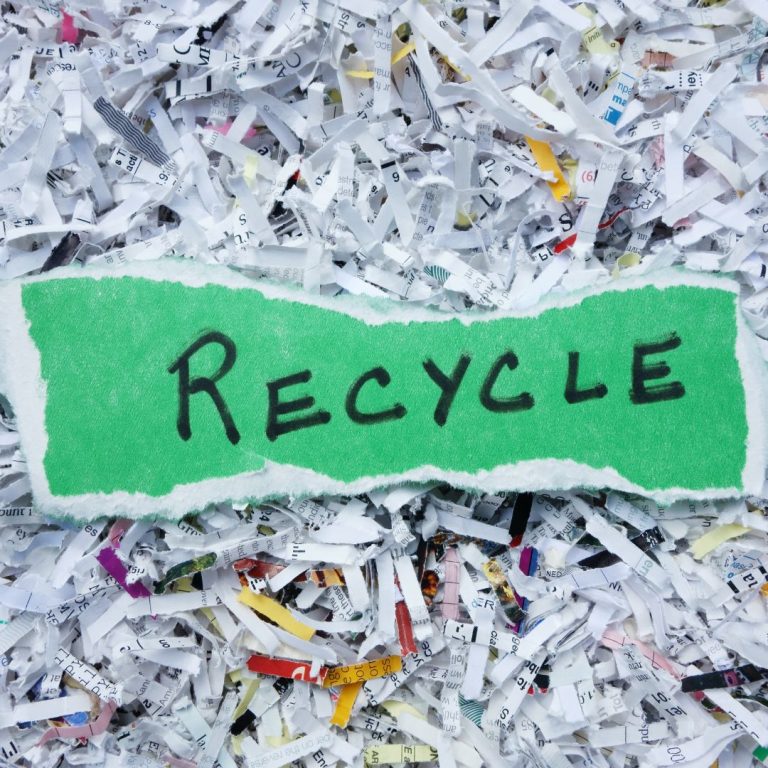 A symbolic image of recycled paper rolls, a green recycling symbol, and Earth in the background, representing paper recycling and its environmental impact.